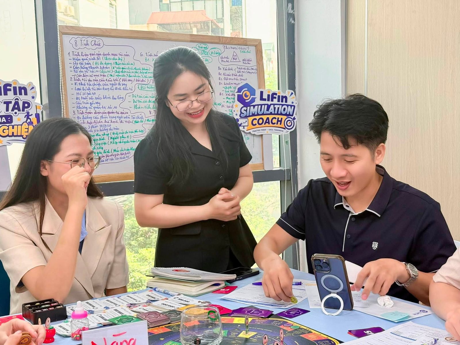 Facilitator đứng cạnh bàn, dẫn dắt người chơi trong buổi LiFin Game